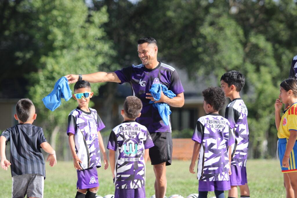 Coach Carlos Longa laughing with young players at training