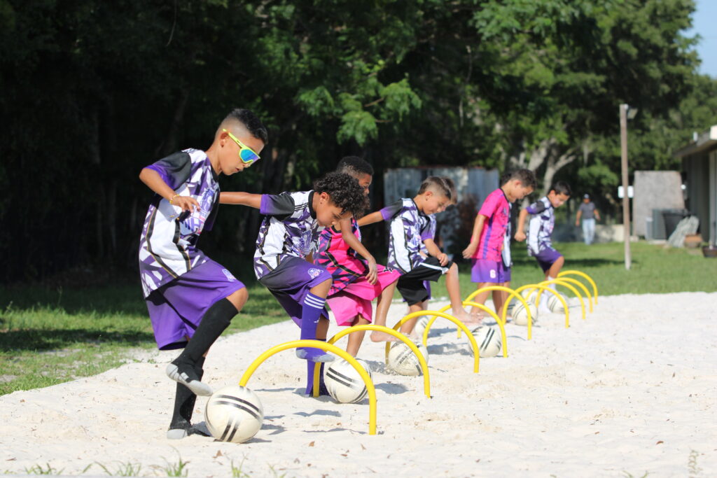 Longa Academy players working on dribbling technique on the sand
